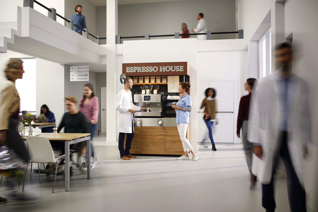 Åpent område med kaffestasjon fra Espresso House og mennesker i samtale og bevegelse.