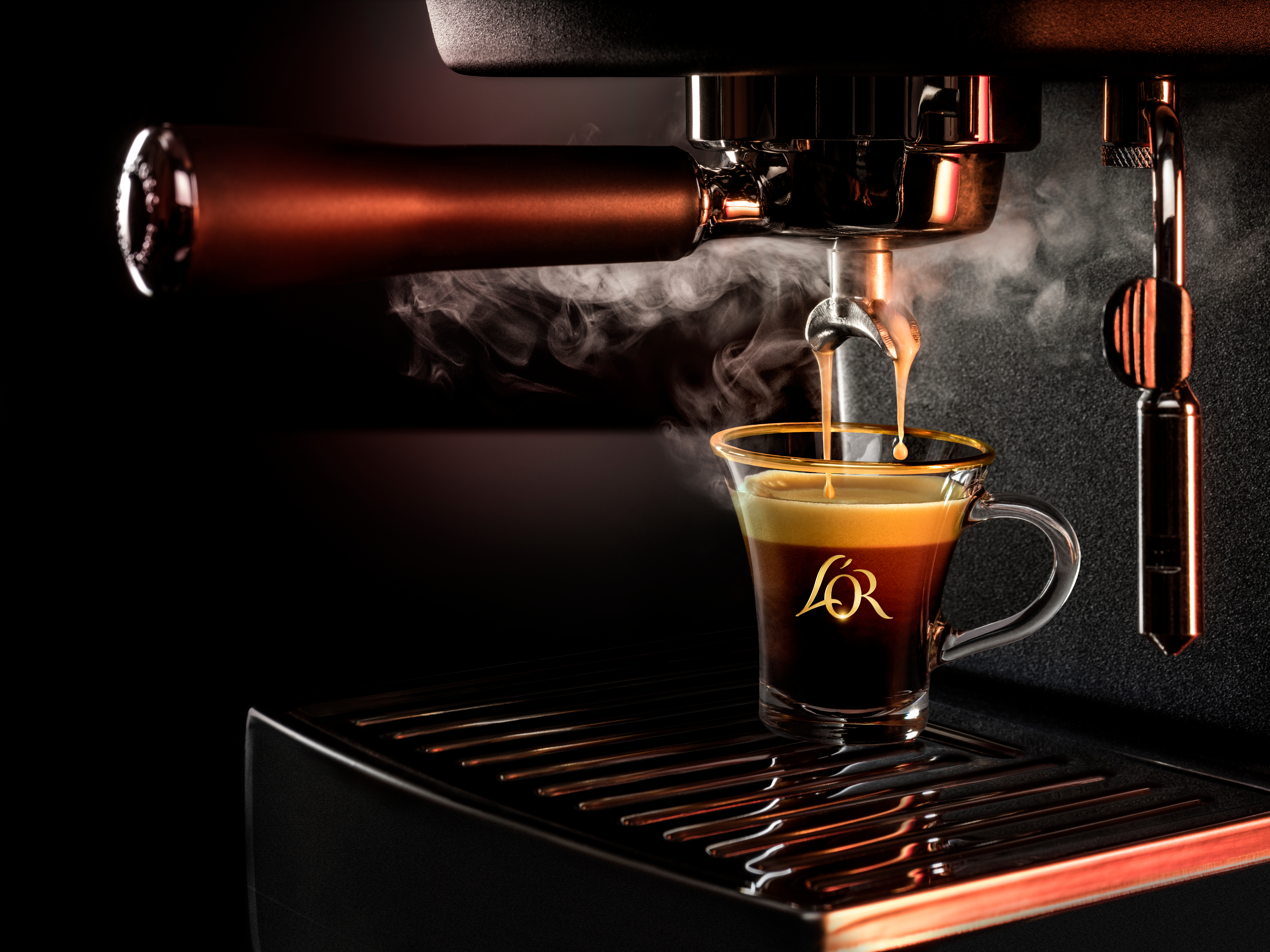 Nærbilde av en espressomaskin som brygger kaffe i en glasskopp med L'OR-logo.