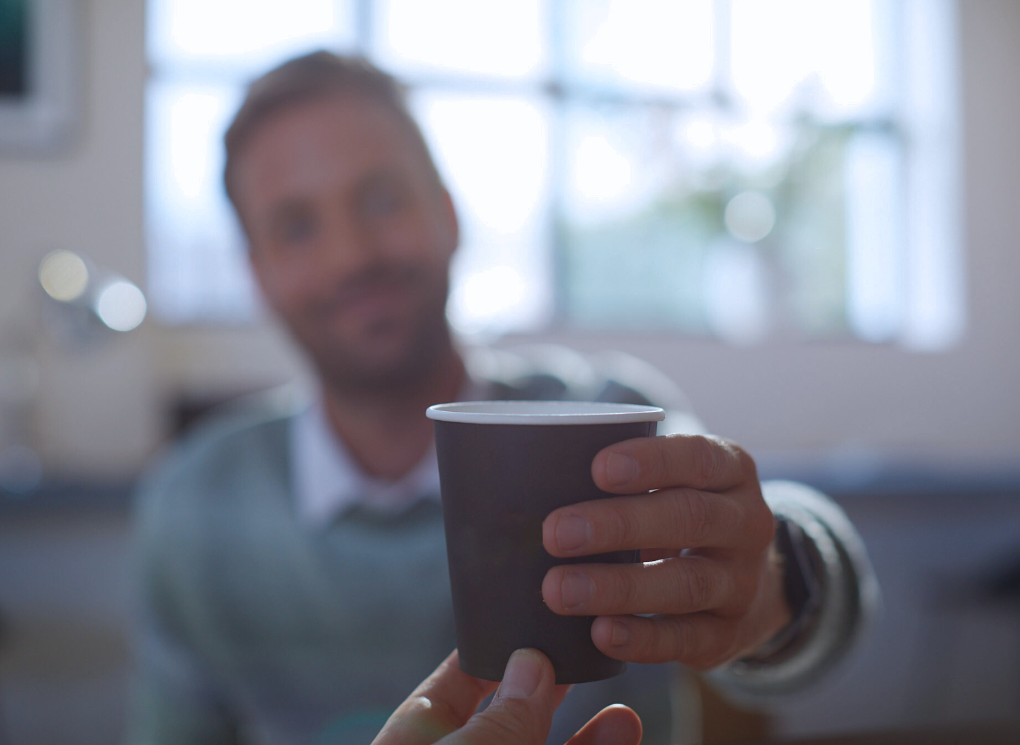Man rekker ut en kopp kaffe