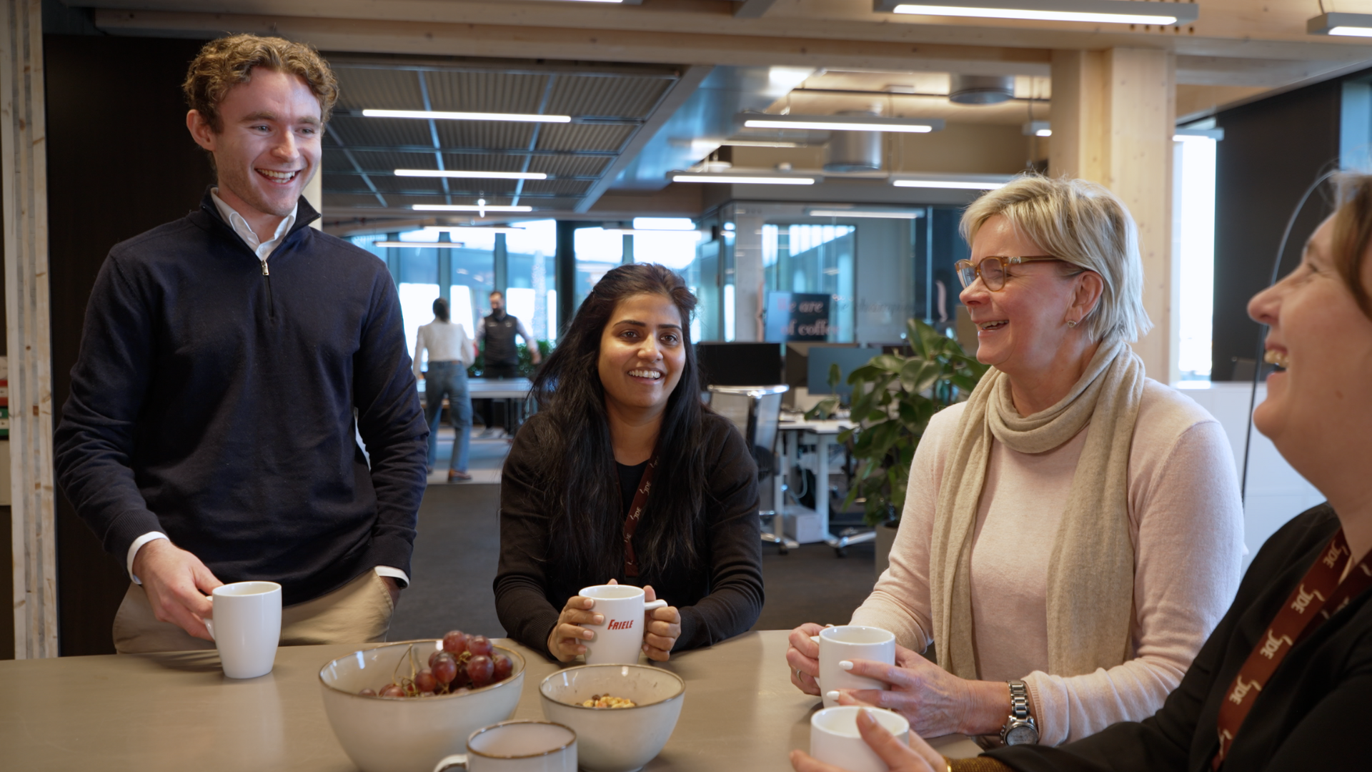 Mennesker ved bord på kontor som drikker kaffe