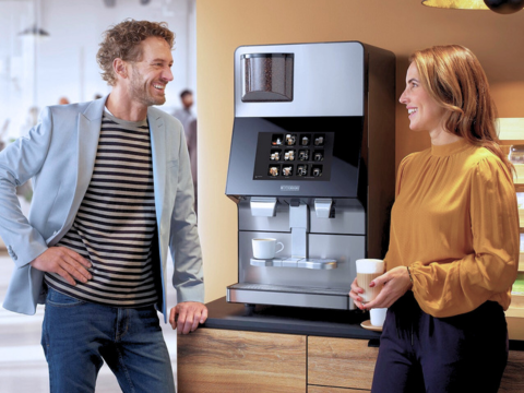Two people talking by a coffee machine